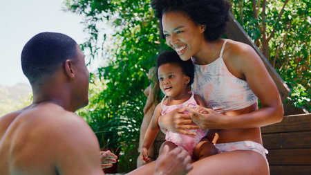 Family With Young Daughter Having Fun On Holiday In Swimming Pool Togetherの写真素材