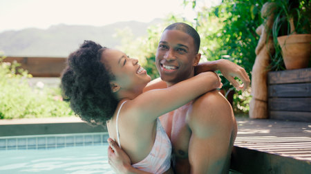 Portrait Of Smiling Couple On Holiday Hugging In Swimming Poolの写真素材