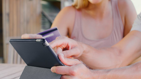 Close Up Of Couple With Credit Card Using Digital Tablet At Home To Book Holiday Or Shop Onlineの写真素材