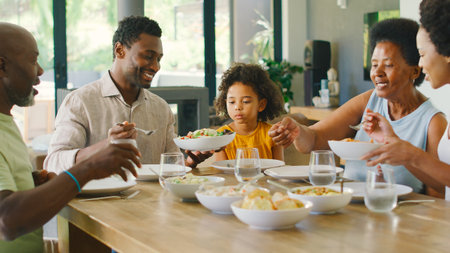 Multi-Generation Family Sitting Around Table Serving Food For Meal At Home