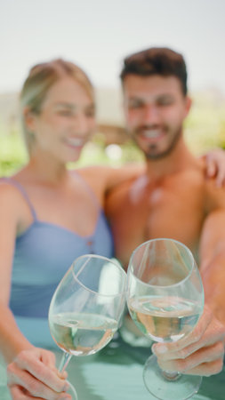 Portrait Of Smiling Couple On Holiday Drinking Wine In Swimming Poolの写真素材