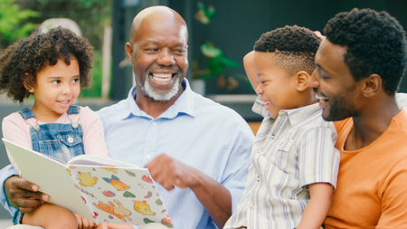 Smiling Multi-Generation Family Reading Book In Garden Togetherの写真素材