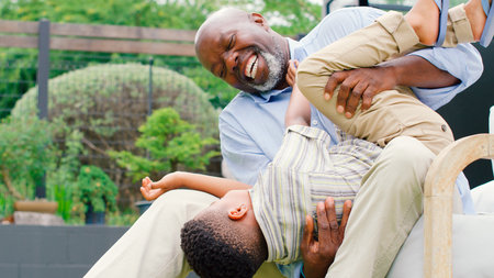 Grandfather Having Fun Playing With Grandson In Garden Holding Him Upside Downの写真素材