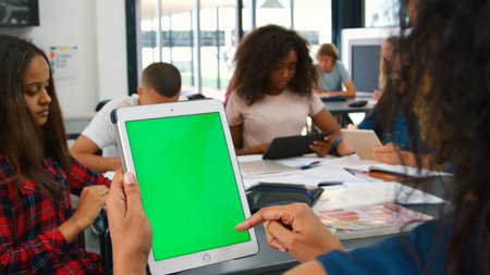 Close Up Of Female High School Teacher With Green Screen Digital Tablet With Students At Deskの写真素材