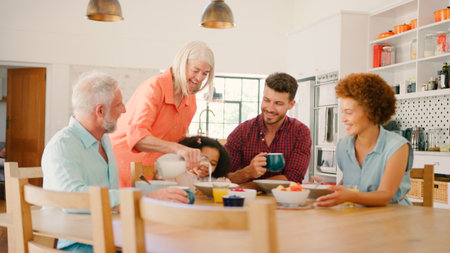 Multi-Generation Family At Home Enjoying Breakfast Sitting Around Table Togetherの写真素材