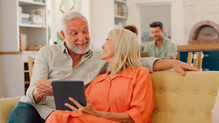 Retired Senior Couple At Home With Digital Tablet Making Purchase Or Booking Using Credit Card