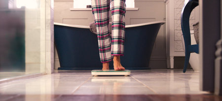 Close Up Of Woman At Home Standing On Bathroom Scalesの写真素材