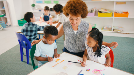 Female Elementary School Teacher Sitting With Students Around Table Paintingの写真素材