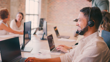 Businessman In Multi-Cultural Business Team Wearing Headset In Customer Support Centre