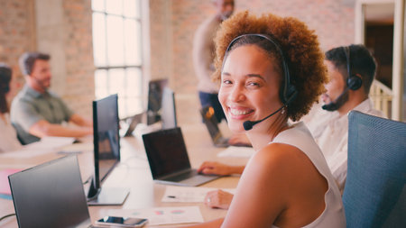 Portrait Of Businesswoman In Multi-Cultural Business Team Wearing Headset In Customer Support Centre