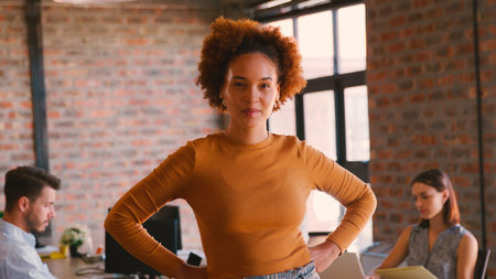 Portrait Of Smiling Businesswoman In Office With Colleagues Working In Background