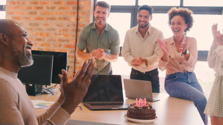 Staff Celebrating Birthday Of Male Colleague In Multi Cultural Office With Cake