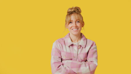 Portrait Of Smiling Casually Dressed Woman With Nose Piercing Against Yellow Studio Backgroundの写真素材