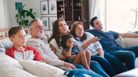 Multi-Generation Family Sitting On Sofa At Home Watching TV Together