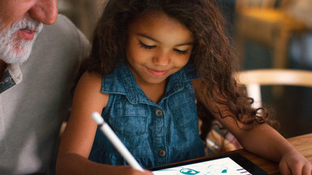 Close Up Of Grandfather With Granddaughter Drawing On Digital Tablet At Home