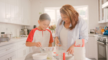 Grandmother And Grandson In Kitchen At Home Having Fun Baking Together