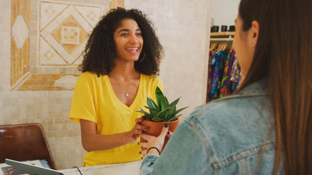 Female Customer Buying Plant From Sales Assistant In Independent Gift Store