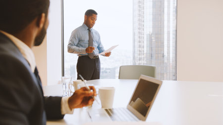 Two Businessmen Sitting Around Table Meeting In Modern Open Plan Office