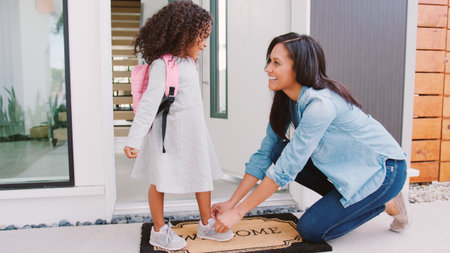 Mother Tying Daughters Shoelaces As She Leaves For School