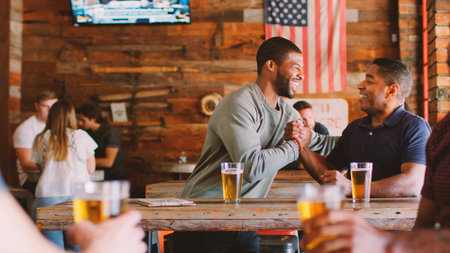 Two Male Friends Meeting In Sports Bar Enjoying Drink Before Gameの写真素材