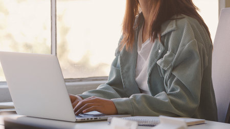 Close Up Of Young Businesswoman At Desk Working On Laptop In Modern Officeの写真素材