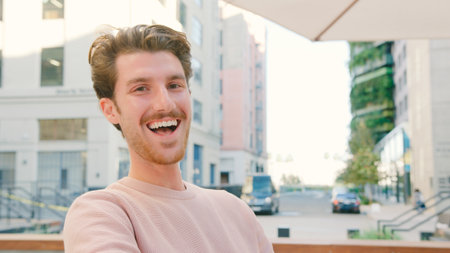 Portrait Of Young Smiling Man Outdoors With City Buildings In Background