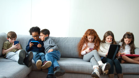 Group Of Boys And Girls Gaming Together On Hand Held Devices At Home