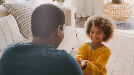 Daughter Giving Father Clay Pot That She Has Made Herself Sitting On Sofa At Homeの写真素材
