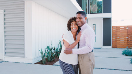 Portrait Of Smiling Mature Couple Standing In Front Of Houseの写真素材