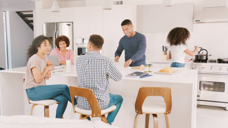 Family With Older Children Sitting Around Kitchen Counter At Home Togetherの写真素材