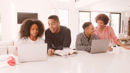 Family With Older Children Using Laptops At Home Togetherの写真素材