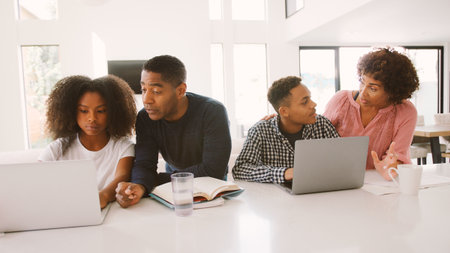Family With Older Children Using Laptops At Home Togetherの写真素材