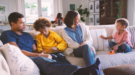 Multi Generation Family At Home With Parents And Children Using Digital Tablet In Foregroundの写真素材