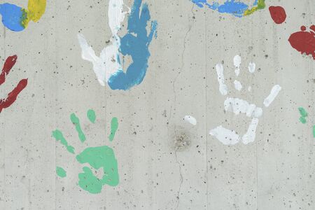 Color hand prints over a concrete wall. red, yellow, green and blue paint. Good as a background image.の写真素材
