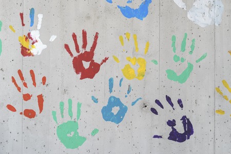 Color hand prints over a concrete wall. red, yellow, green and blue paint. Good as a background image.の写真素材