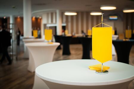 Table on the first plan with yellow flag at conference hallの写真素材