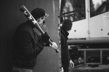 hooligan with the baseball bat in hands ready to attack from hidingの写真素材