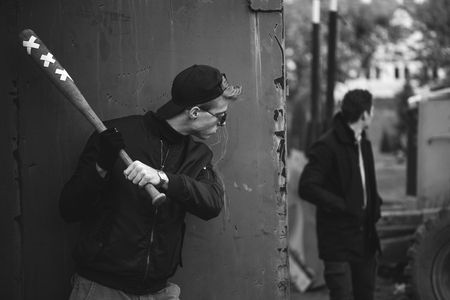hooligan with the baseball bat in hands ready to attack from hidingの写真素材