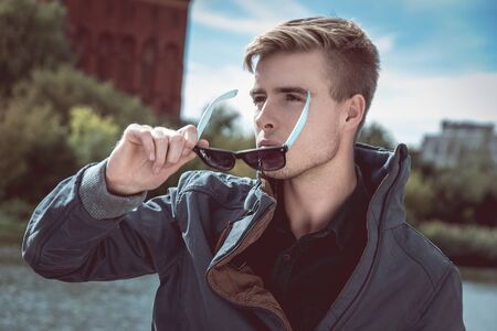 Stylish young handsome man takes off his fancy sunglassesの写真素材