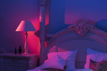 Luxurious minimalist art décor Bedroom with royal bed, pink and blue light with stylish night lamp at the wooden tableの写真素材