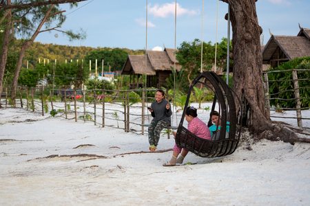 Cambodian girls are siting on the swing, they are checking the smartphone during their break. Many Khmer people living in the island, working in the resorts. Usually they are spending a lot of time. 13 September 2017, Koh Rong Samloem Cambodia, Asia.のeditorial素材