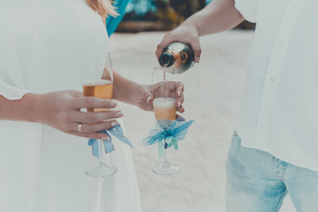 Celebration at the beach. Man pours champagne into the glassesの写真素材