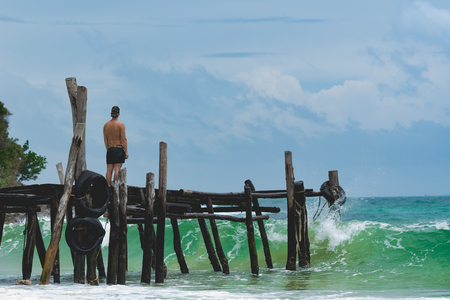 Man standing at the pier and watching the ocean waves. Lazy beach, Koh Rong Samloem. Cambodia.の写真素材