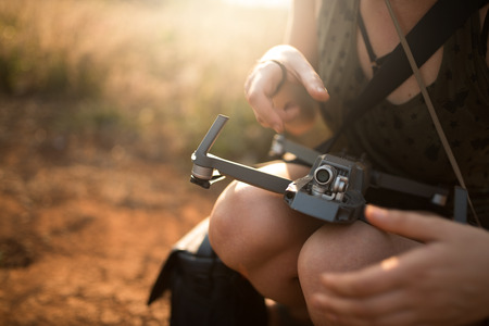 Woman preparing drone to fly checking battery and lens.の写真素材