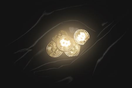 Golden shiny bitcoin lies on the dark material.