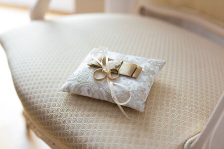 Golden wedding rings lies on a small decorated pillowの写真素材