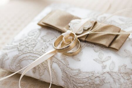 Golden wedding rings lies on a small decorated pillowの写真素材