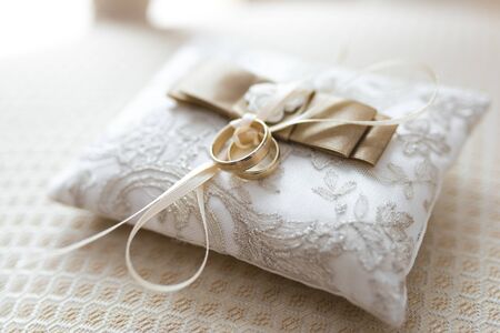 Golden wedding rings lies on a small decorated pillowの写真素材