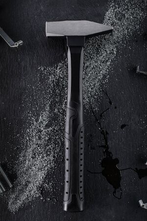 Black hammer made of reinforced steel placed on a black stone background.の写真素材