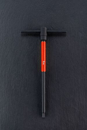 Professional reinforced black matt T-shape wrench placed on a dark background. T-type handle Tool used in a workshop. View from the top.の写真素材